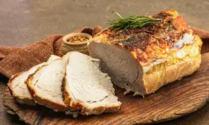 Soczysty schab pieczony w piekarniku, pokrojony w plastry, z gałązką rozmarynu i miseczką przypraw.