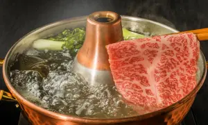 Kawałek marmurkowej wołowiny kobe zanurza się w bulgoczącym bulionie. Zastanawiasz się, ile kosztuje kilogram wołowiny kobe?