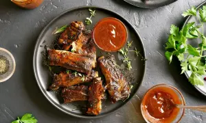 Pyszne, pieczone żeberka w sosie BBQ, podane z ziołami i sosem. Idealne na obiad!