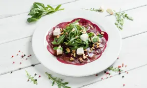 Eleganckie carpaccio z buraka z fetą, orzechami i rukolą, polane aromatycznym sosem.