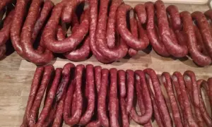 Dwie linie świeżych, czerwonych kiełbas na drewnianym blacie. Zastanawiam się, ile soli, pieprzu i czosnku do kiełbasy.