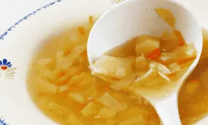 Łyżka nabiera porcję pysznego, domowego kapuśniaku z ziemniakami i marchewką. Idealny sposób, jak przyprawić kapuśniak, by był aromatyczny.