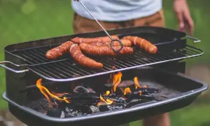 Kiełbaski skwierczą na grillu, idealne miejsce, gdzie zrobić grilla w ogrodzie.