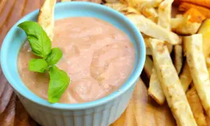 Pikantny sos w niebieskiej miseczce, idealny jako dodatek do pieczonych frytek ziemniaczanych i marchewkowych. Co pasuje do frytek? Ten sos!