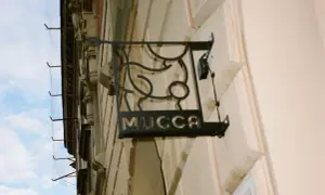 Czarna, metalowa tablica z napisem "MUCCA" i stylizowanym bykiem. Idealne miejsce, gdzie na steka w Krakowie.
