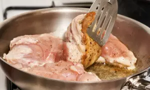 Smażony kurczak na patelni. Czy kurczaka smażyć pod przykryciem? Kawałki mięsa są rumiane i gotowe do dalszej obróbki.