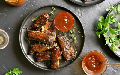 Pyszne, pieczone żeberka w sosie BBQ, podane z ziołami i sosem. Idealne na obiad!