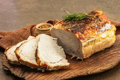 Soczysty schab pieczony w piekarniku, pokrojony w plastry, z gałązką rozmarynu i miseczką przypraw.