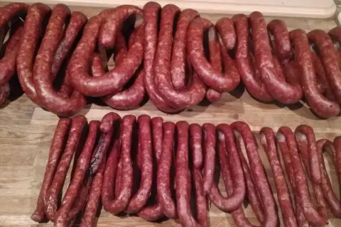 Dwie linie świeżych, czerwonych kiełbas na drewnianym blacie. Zastanawiam się, ile soli, pieprzu i czosnku do kiełbasy.