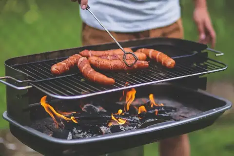Kiełbaski skwierczą na grillu, idealne miejsce, gdzie zrobić grilla w ogrodzie.