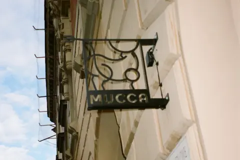 Czarna, metalowa tablica z napisem "MUCCA" i stylizowanym bykiem. Idealne miejsce, gdzie na steka w Krakowie.