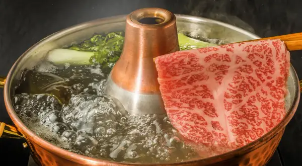 Kawałek marmurkowej wołowiny kobe zanurza się w bulgoczącym bulionie. Zastanawiasz się, ile kosztuje kilogram wołowiny kobe?