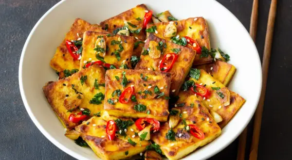 Złocisty, chrupiący tofu na patelni, posypany chili i sezamem. Idealny sposób, by dowiedzieć się, ile smażyć tofu na patelni dla najlepszego efektu.