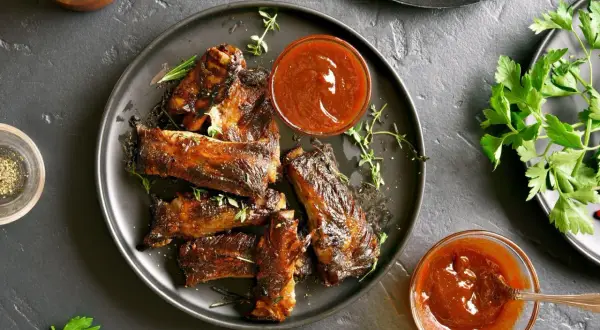 Pyszne, pieczone żeberka w sosie BBQ, podane z ziołami i sosem. Idealne na obiad!