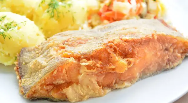 Złocisty, chrupiący kawałek ryby, idealny do nauki jak smażyć halibuta w dzwonkach. Podany z purée ziemniaczanym i surówką.