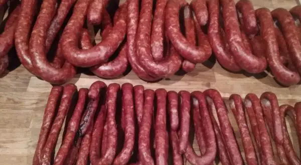 Dwie linie świeżych, czerwonych kiełbas na drewnianym blacie. Zastanawiam się, ile soli, pieprzu i czosnku do kiełbasy.