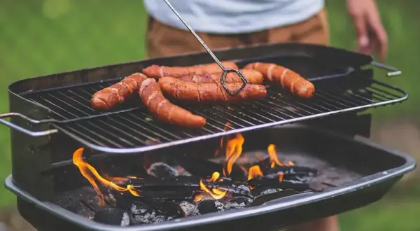 Kiełbaski skwierczą na grillu, idealne miejsce, gdzie zrobić grilla w ogrodzie.