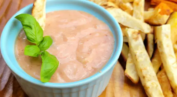 Pikantny sos w niebieskiej miseczce, idealny jako dodatek do pieczonych frytek ziemniaczanych i marchewkowych. Co pasuje do frytek? Ten sos!