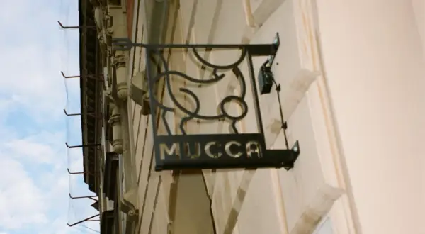 Czarna, metalowa tablica z napisem "MUCCA" i stylizowanym bykiem. Idealne miejsce, gdzie na steka w Krakowie.
