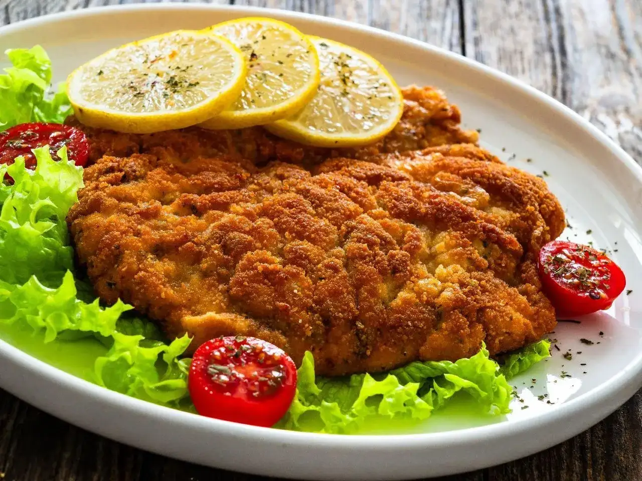 Złocisty kotlet schabowy na sałacie z pomidorkami i cytryną. Idealny sposób, jak odświeżyć kotlety schabowe na obiad.
