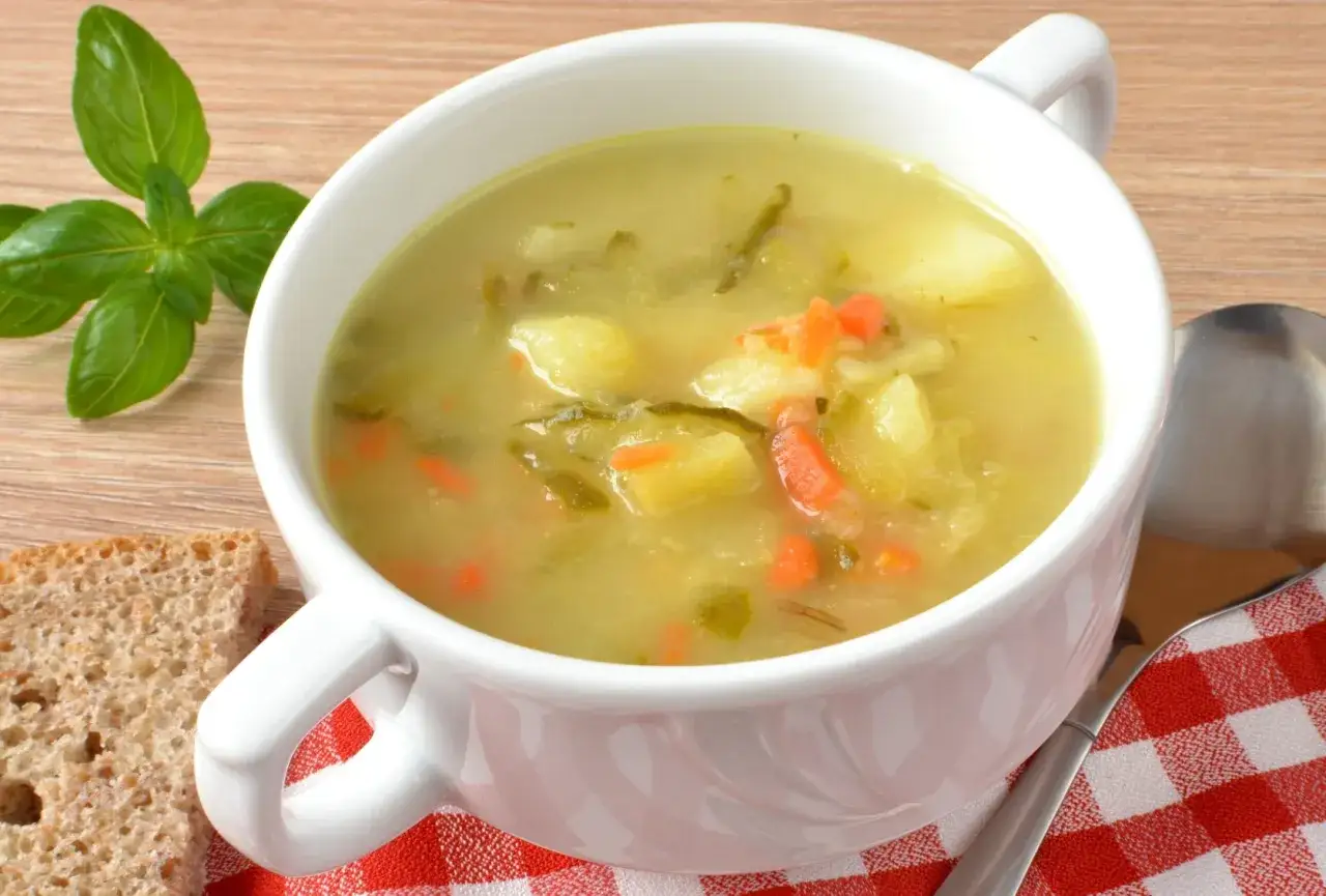 Zupa ogórkowa z ziemniakami i marchewką, podana z chlebem. Idealna, by dowiedzieć się, jak przyprawić zupę ogórkową.