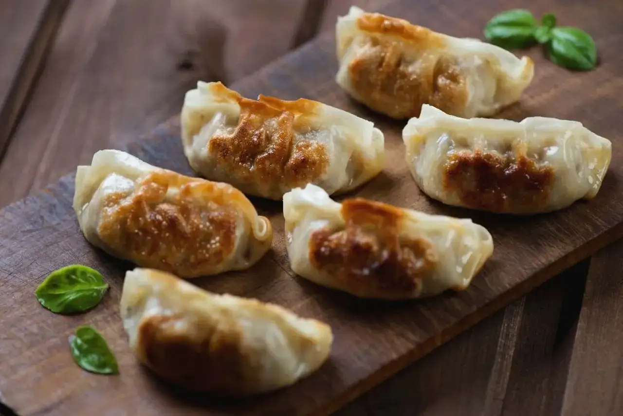 Złociste, chrupiące pierożki na desce. Idealne, gdy wiesz, jak podsmażyć pierogi na patelni.