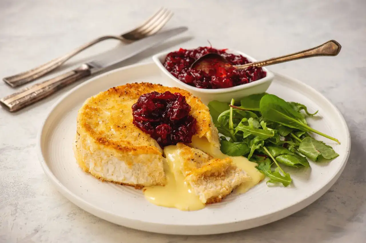 Idealnie usmażony camembert z chrupiącą panierką, polany konfiturą żurawinową, podany z rukolą. Pyszny sposób, jak usmażyć camembert.
