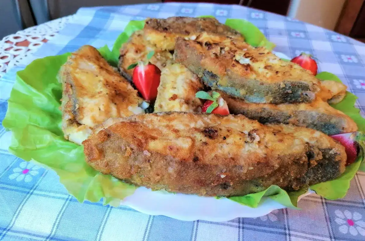 Usmażony halibut na liściach sałaty, ozdobiony truskawkami. Idealny przykład, jak przygotować halibuta do smażenia.