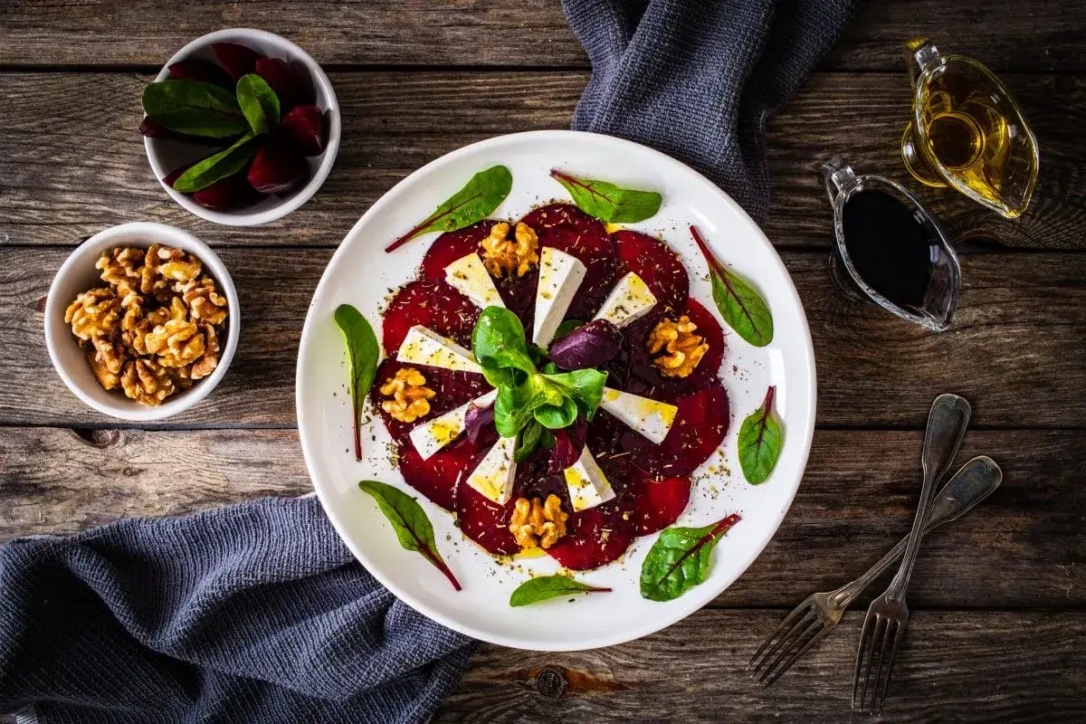 Eleganckie carpaccio z buraka z serem feta i orzechami włoskimi, podane z dressingiem.