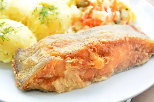 Złocisty, chrupiący kawałek ryby, idealny do nauki jak smażyć halibuta w dzwonkach. Podany z purée ziemniaczanym i surówką.