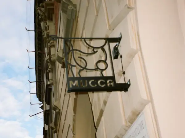 Czarna, metalowa tablica z napisem "MUCCA" i stylizowanym bykiem. Idealne miejsce, gdzie na steka w Krakowie.